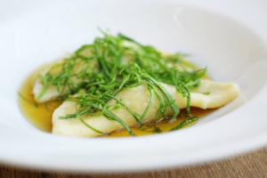 Gnocchi mit frischen Kräutern und Butter in weißer Schüssel.