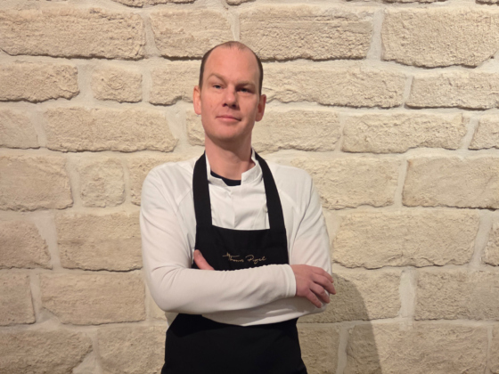 Thomas Pugel in Kochschürze vor Steinmauer, professioneller Koch oder Küchenchef.
