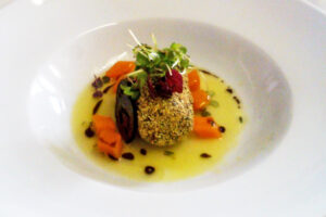 Gebackener Fisch mit Gemüse und Kräutern auf weißem Teller.