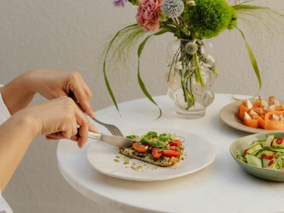 Frühstückstisch mit frischen Salaten, Blumen und vegetarischer Pizza.